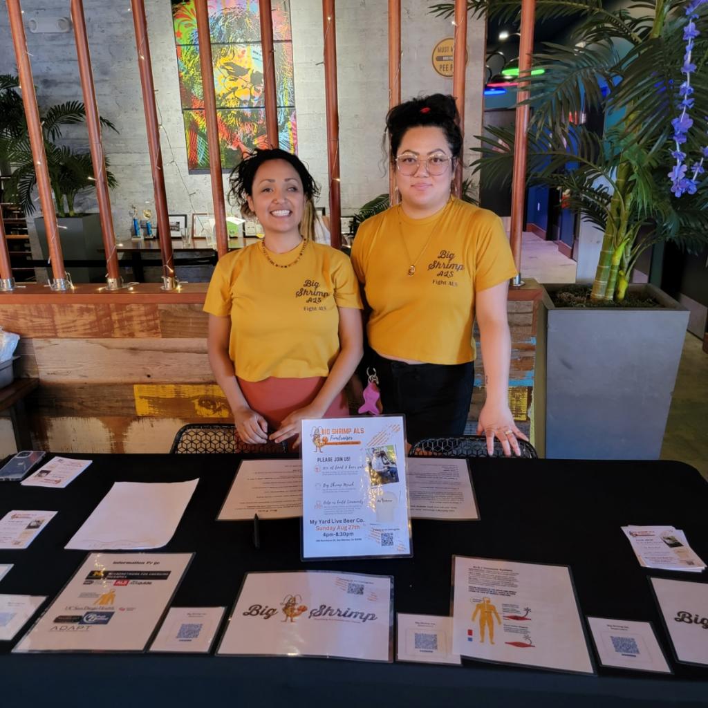 Two women standing next to a table with papers on it.